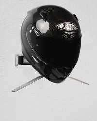 Black motorcycle helmet mounted on a gray wall with a holder