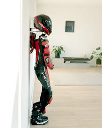 Side view of the Pro V4 holding a red and black motorcycle suit and helmet, mounted against a wall.