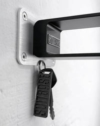 Keychain and keys attached to a wall-mounted aluminum bracket with 'SUITBASE' branding.