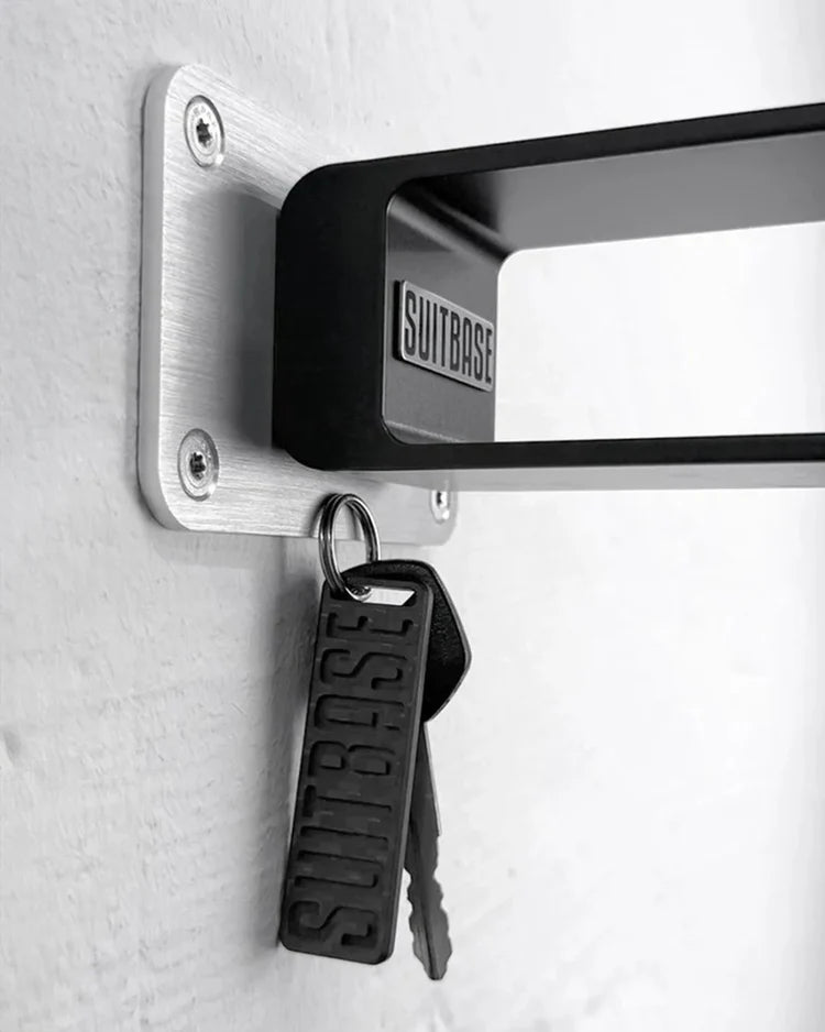 Keychain and keys attached to a wall-mounted aluminum bracket with 'SUITBASE' branding.
